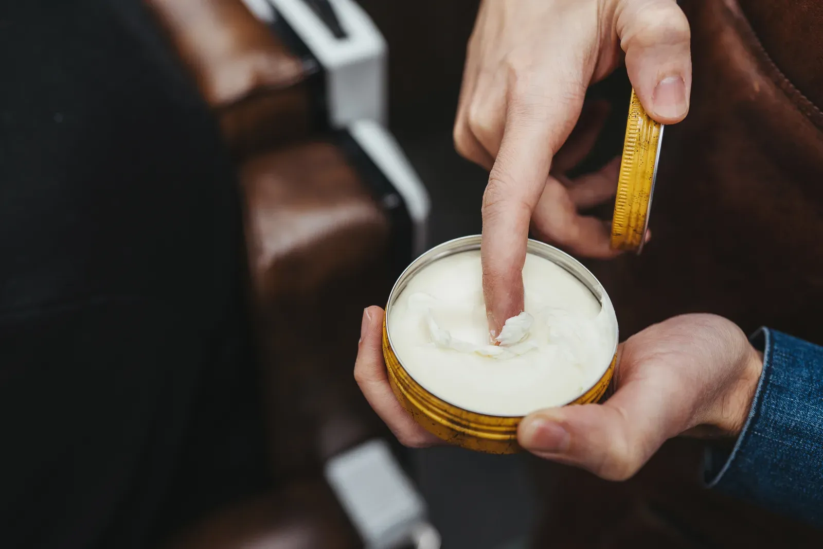 Barber scooping styling pomade from a tin